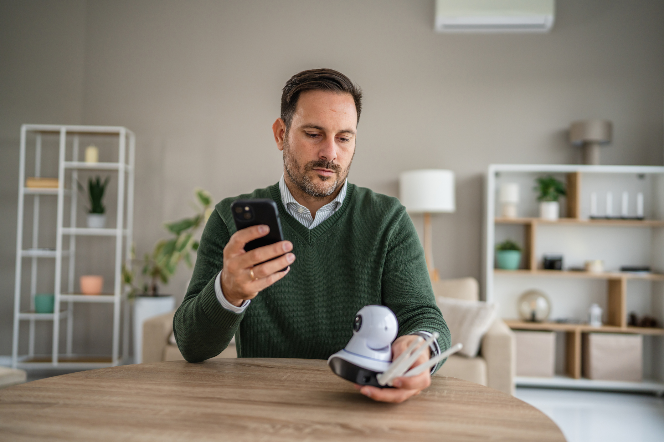 Man configuring a security camera for home surveillance, connecting the smart device to his smart phone using modern technology and a secure internet of things network