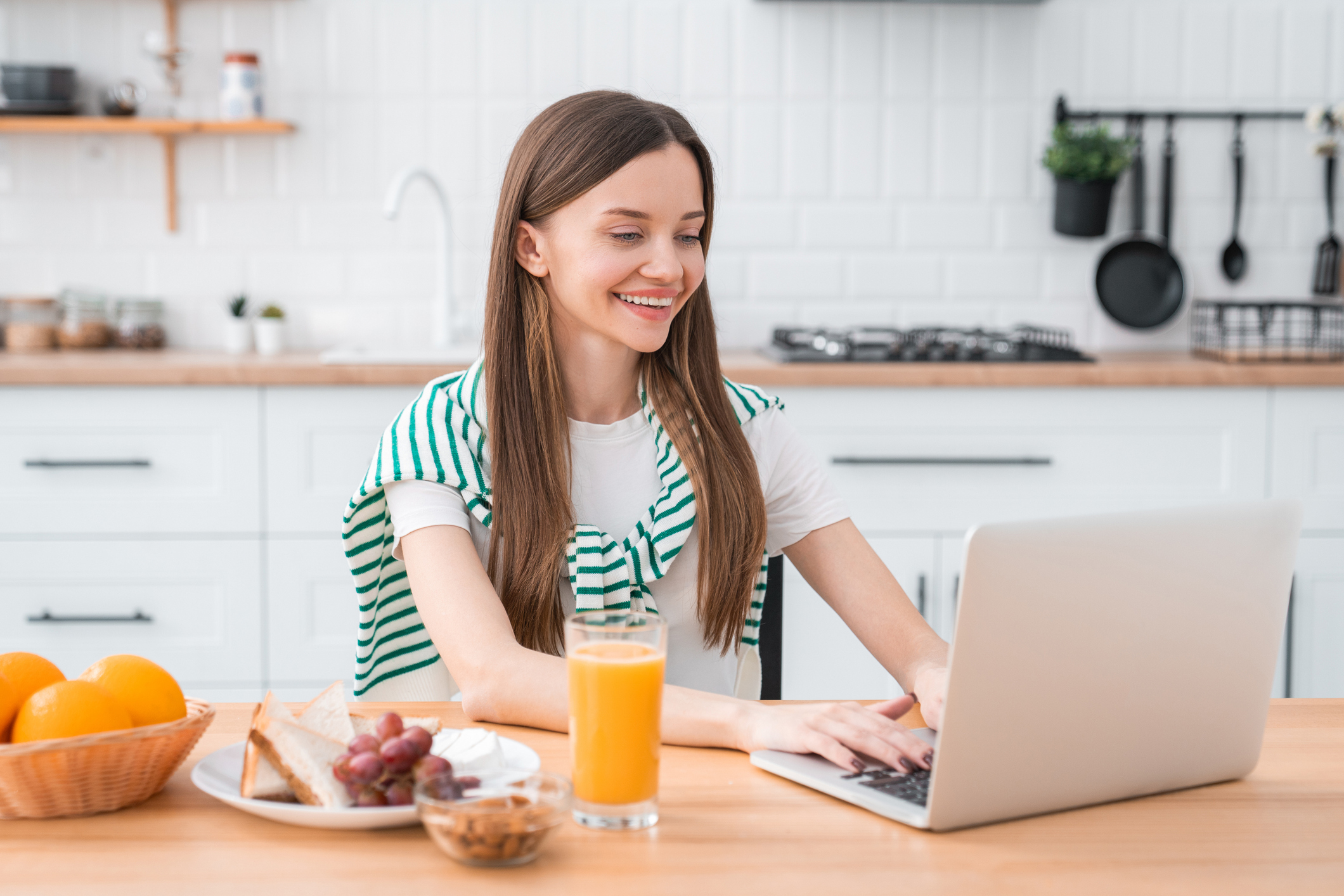 Smiling woman using laptop with breakfast